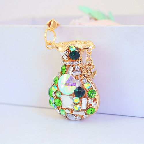 Green faceted stones and clear accents cover a gold-tone money bag charm.