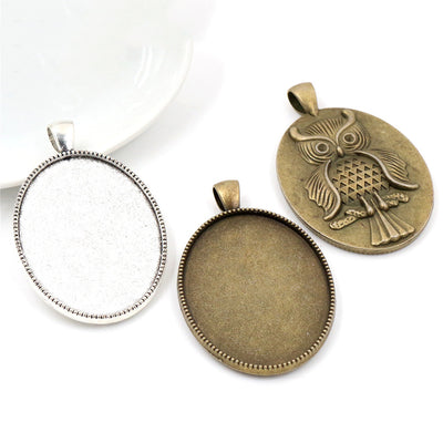 Overview of oval pendant trays with raised owl designs on the reverse on a light background