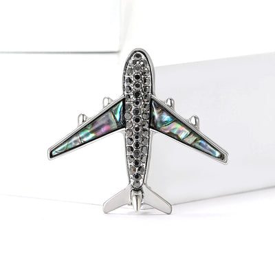 A silver tone airplane with crystal body and shell-inlay wings shown on a white background.