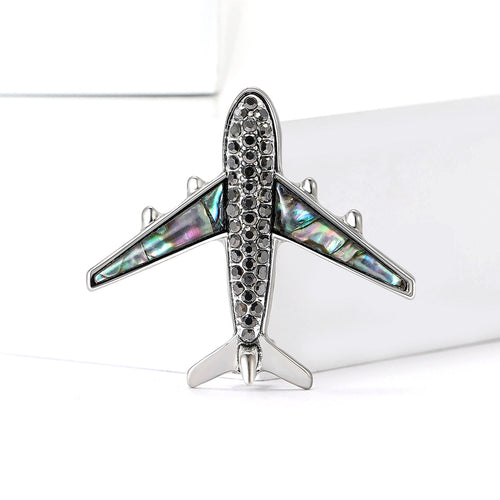 A silver tone airplane with crystal body and shell-inlay wings shown on a white background.