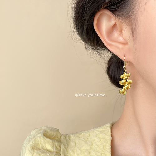 Gold-tone layered-ginkgo-leaf cluster hooks shown worn on an ear.