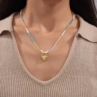Pastel beaded necklace with gold heart pearl pendant worn on neck