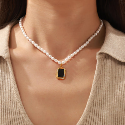 Model wearing pearl necklace with black gold-framed rhinestone pendant