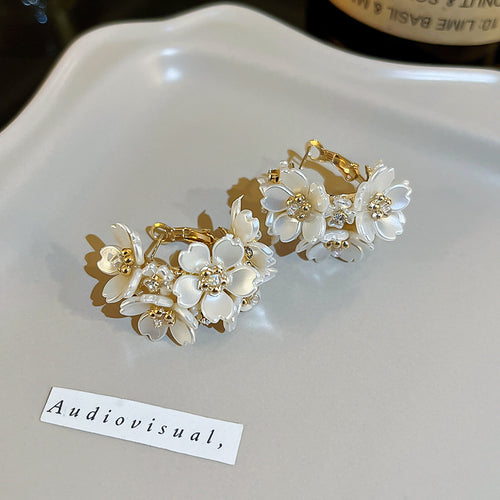 Gold White Floral Crystal Hoop Earrings Polished Metal Jewelry shown on a neutral display