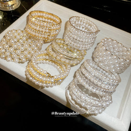 Assorted multi-row pearl rhinestone cuffs on white tray