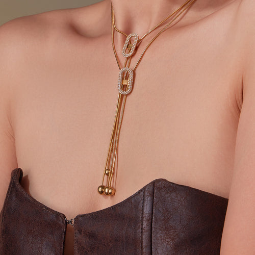 Model wearing two layered gold oval zircon Y-necklaces on bare skin