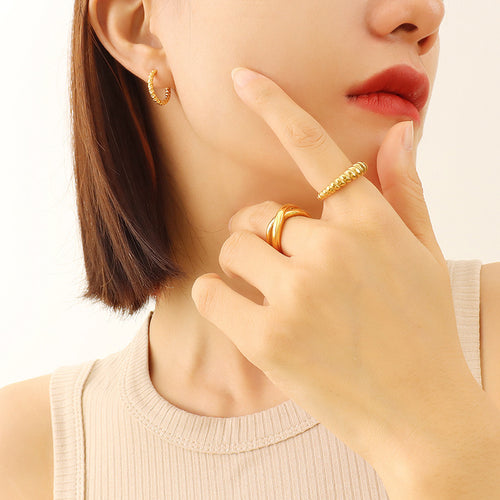 Model wearing gold textured small hoop earring with gold rings
