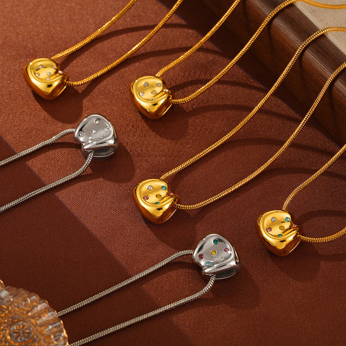 Group of gold and steel snake-chain necklaces with cushion pendants on brown fabric
