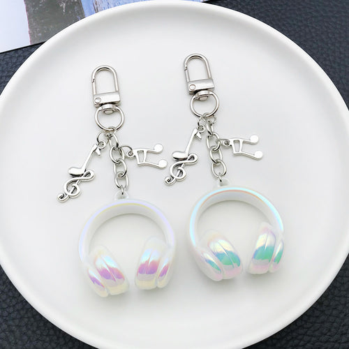 Styled close-up of solid white headphone and music note clip keychain eight-color showing colors and surface details