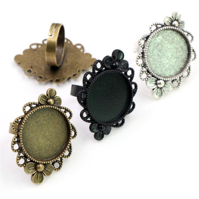 Assorted ornate oval bezel ring blanks in four metal finishes arranged together on a plain background