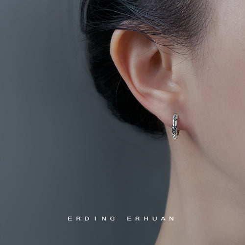 Silver-tone blue-stone star-pattern huggie hoops shown worn on an ear.