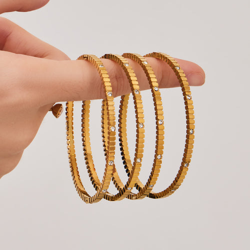 Hand holding stack of gold gear-texture crystal bangles