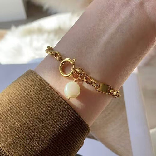 Gold plated square link bracelet with pearl charm worn on wrist