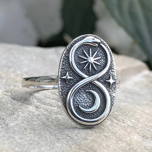 Antique silver oval ring snake sun moon design close-up on stone