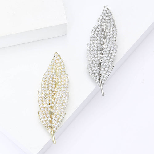 Gold and silver pearl leaf brooches side by side on white blocks