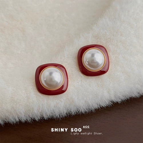 Wine red enamel pearl studs on fluffy cream fabric