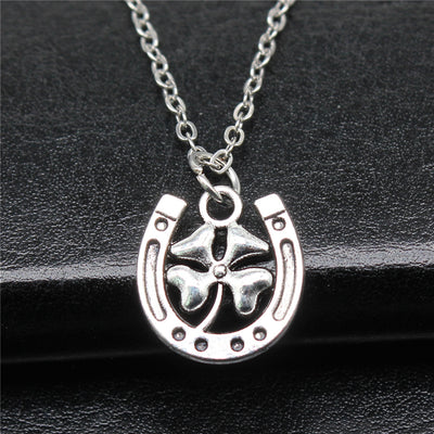 Close-up of horseshoe clover pendant necklace showing a silver-tone horseshoe pendant with a clover center on a chain