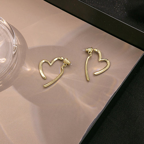 Gold open heart stud earrings with hanging bars on beige tray