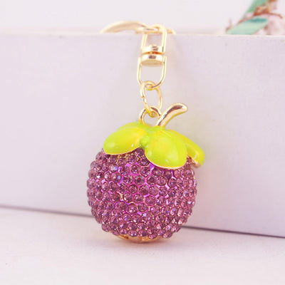 Front view of the purple rhinestone fruit charm beneath glossy green leaves.