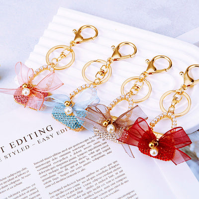 A front product view shows the bow handbag keychain with its visible ornament and hanging hardware.