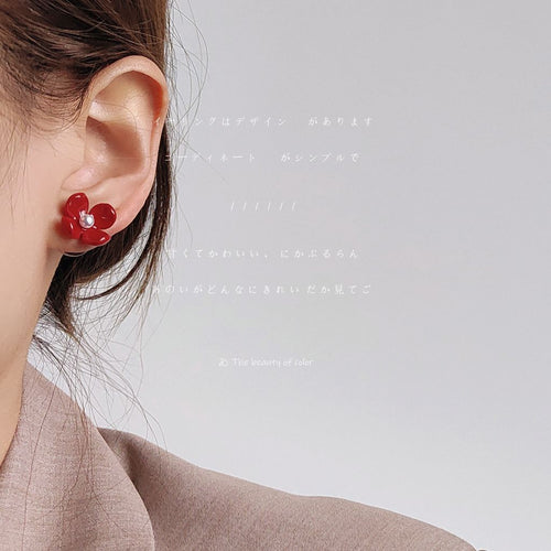Red four-petal flower stud earring worn on ear profile