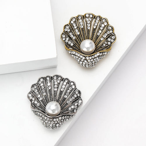 Gold and silver pearl shell rhinestone brooches side by side on white