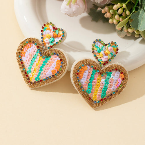 Sequin rainbow heart drop earrings shown at an angle with rhinestone accents