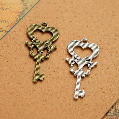 Second product image of the ornate heart skeleton key pendant showing a long key topped by a ribbed open heart and scrol