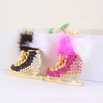 Two jeweled ice skate charms in black and pink stand side by side.