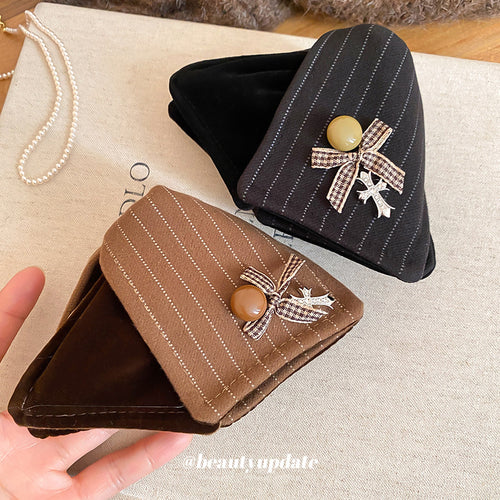 Hand holds brown and black pinstripe triangle claw clips with bow cross charms