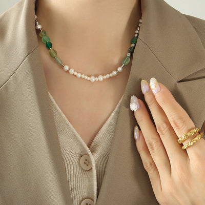 Model wearing silver pearl and green stone beaded necklace with beige blazer