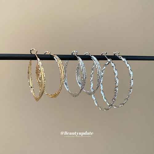 textured metal hoop earrings in three twisted designs shown in the main product view