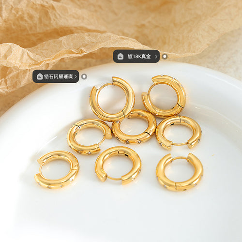 Multiple gold star huggie hoops piled on white dish
