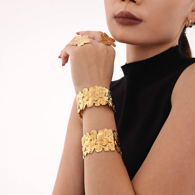 Model wearing gold floral open cuff bracelets and flower rings