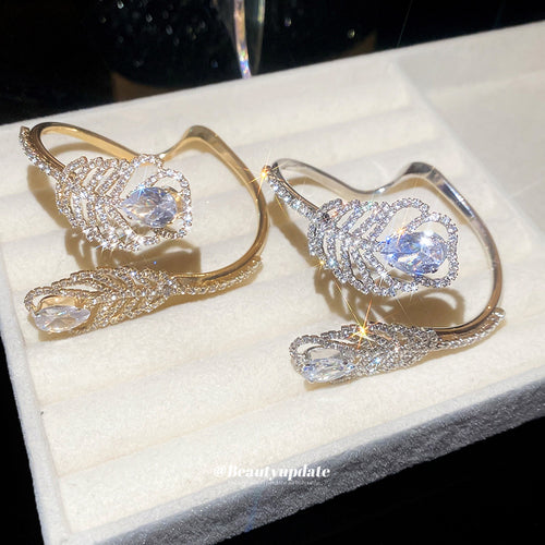 Gold and silver feather teardrop crystal open cuffs on white jewelry pad