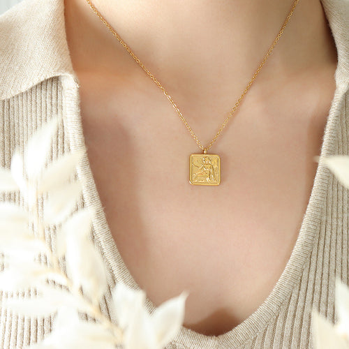 Gold square angel pendant necklace worn on beige knit top