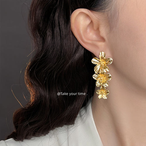 Gold flower cascade earring worn on ear side profile