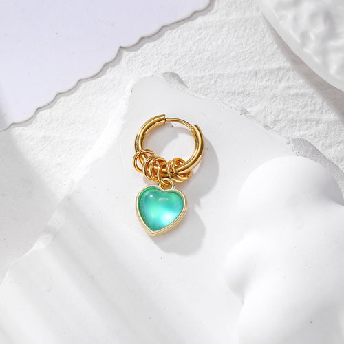 Green pearlized heart charm dangling from gold hoop earring
