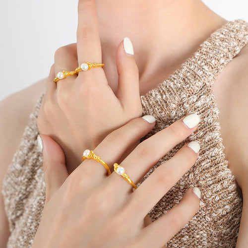 Hands wearing multiple gold irregular pearl open rings stacked on fingers