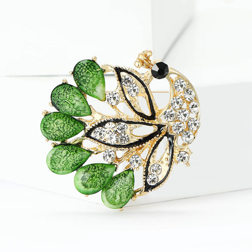 Green peacock brooch angled on white display blocks