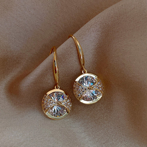 Gold circular clear stone hook earrings pair angled on cloth
