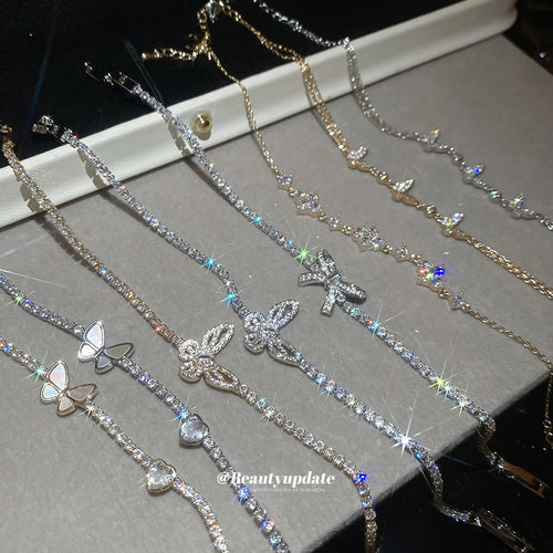 Assorted butterfly tennis and chain bracelets laid on gray tray