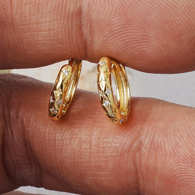 Gold star engraved mini huggie hoops held on fingertips