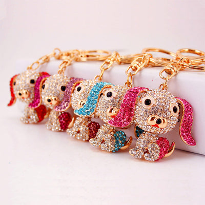 Five crystal-covered dog keychains arranged in red, magenta, purple, blue, and pink.