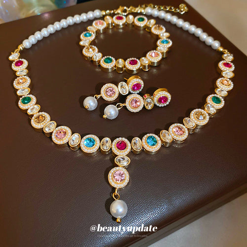 Gold multicolor crystal pearl necklace bracelet and earrings on brown tray
