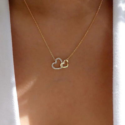 Gold double interlocking heart pendant necklace worn on collarbone