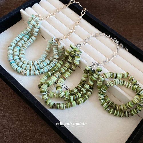 Mint gold-chain and green silver-chain shell disc necklaces with green bracelet in tray