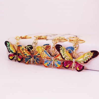 Four multicolor rhinestone butterfly keychains arranged in a row.