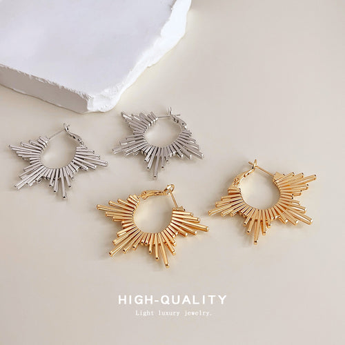 Gold and silver sunburst radial bar hoops on beige surface