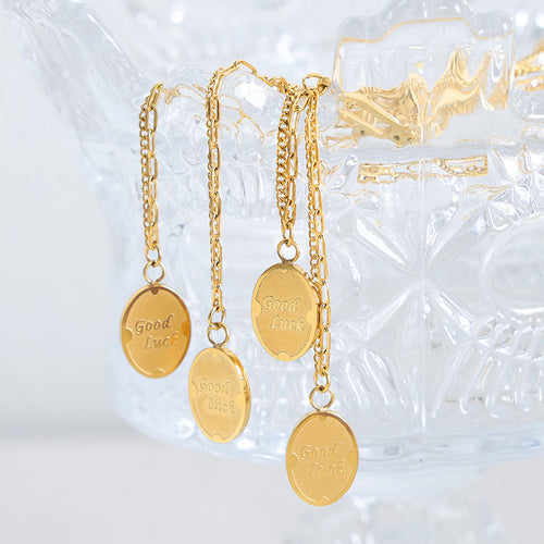 Four gold Good Luck oval pendants hanging over glass crystal bowl